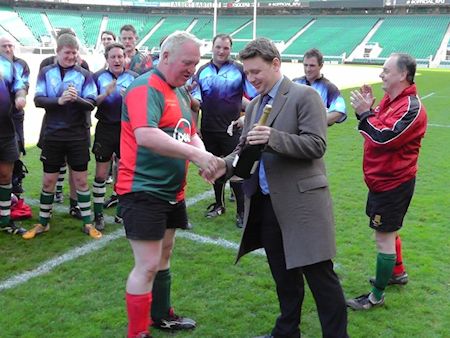 Mike Penning is presented with a bottle of champaign as 'Man of the Match' at the annual Commons & Lords charity rugby event